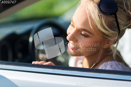 Image of happy teenage girl or young woman in car