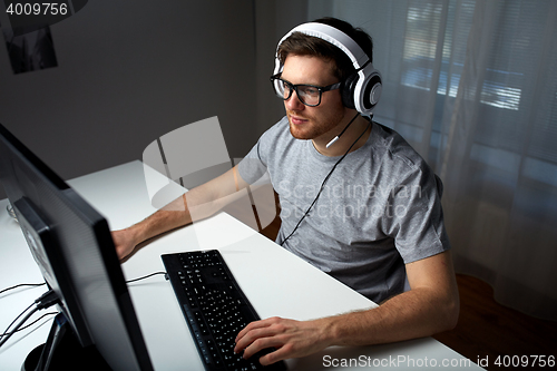 Image of man in headset playing computer video game at home