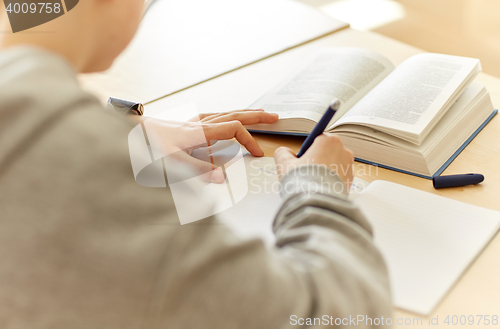 Image of close up of student writing to notebook at school