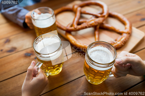 Image of close up of hands with beer mugs at bar or pub