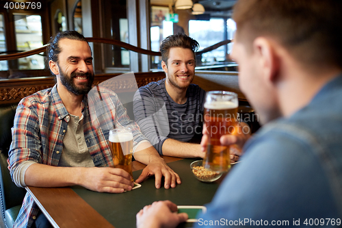 Image of happy male friends drinking beer at bar or pub