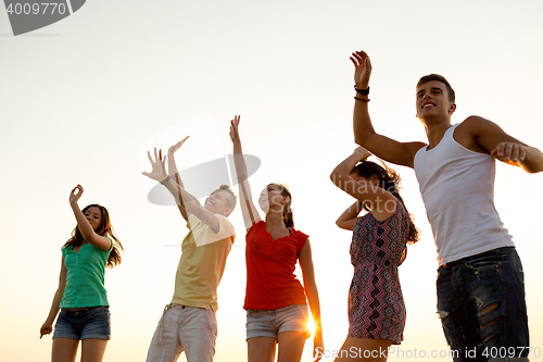 Image of smiling friends dancing on summer beach