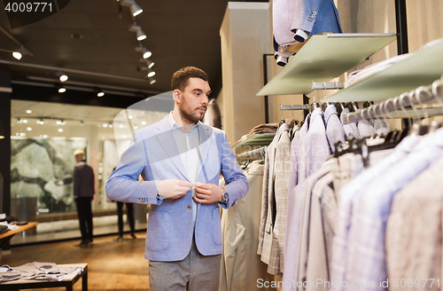Image of happy young man trying jacket on in clothing store