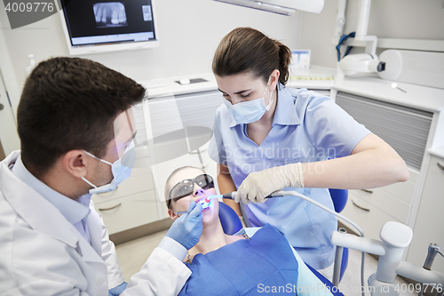 Image of dentists treating male patient teeth at clinic