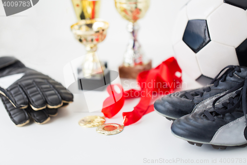 Image of close up of football, boots, gloves, cup and medal