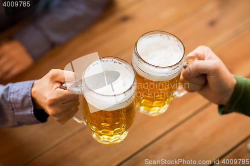 Image of close up of hands with beer mugs at bar or pub