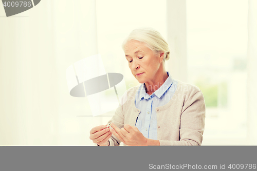 Image of senior woman with glucometer checking blood sugar