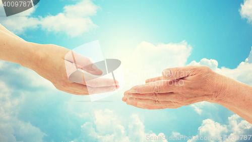 Image of close up of senior and young woman hands