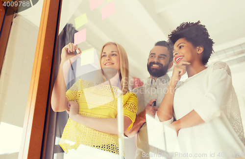 Image of happy creative team writing on stickers at office