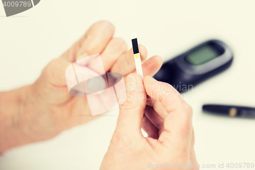 Image of senior woman with glucometer checking blood sugar