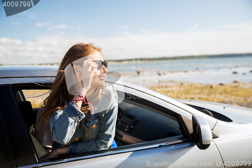 Image of happy teenage girl or young woman in car