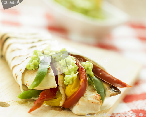 Image of delicious wrap tortilla with spicy chicken vegetables guacamole