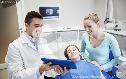 Image of dentist showing tablet pc to girl and her mother