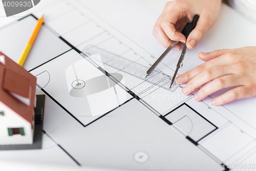 Image of close up of hands with compass measuring blueprint