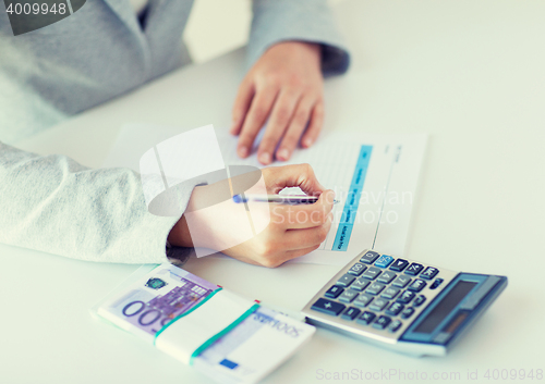 Image of close up of hands counting money with calculator