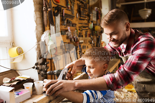 Image of father and son with plane shaving wood at workshop