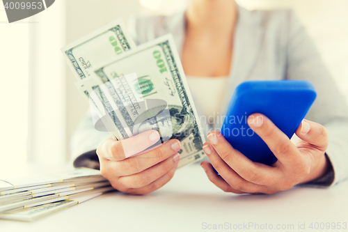 Image of close up of woman hands with smartphone and money