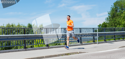 Image of smiling young man running at summer seaside