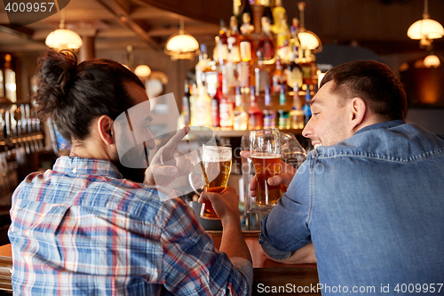 Image of happy male friends drinking beer at bar or pub