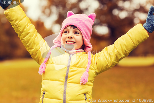 Image of happy little girl with raised hands outdoors