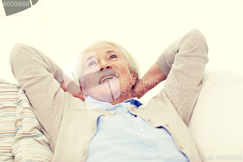 Image of happy senior woman resting on sofa at home