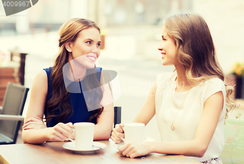 Image of smiling young women with coffee cups at cafe