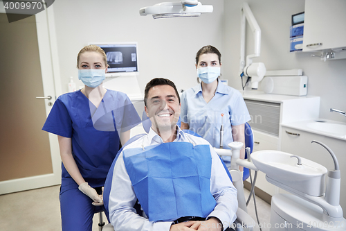 Image of happy female dentists with man patient at clinic