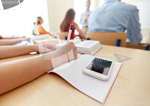 Image of student with smartphone and notebook at school