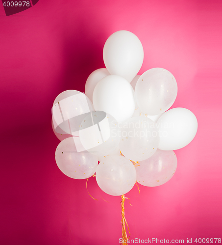 Image of close up of white helium balloons over pink