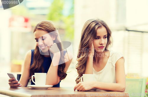 Image of women with smartphones and coffee at outdoor cafe