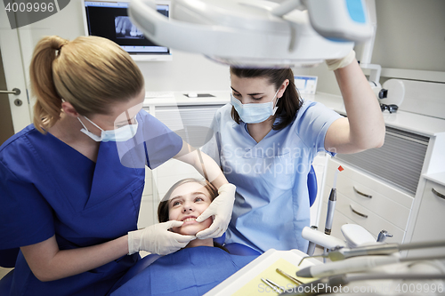 Image of happy female dentist with patient girl at clinic