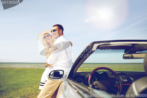 Image of happy couple hugging near cabriolet car at sea