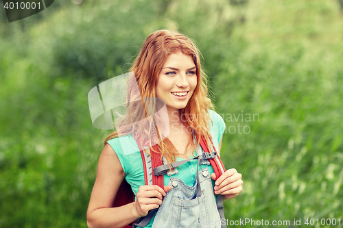 Image of smiling young woman with backpack hiking in woods