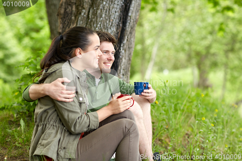 Image of happy couple with cups drinking tea in nature