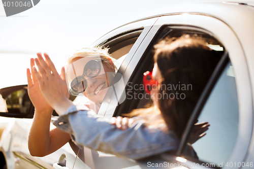 Image of happy teenage girls or women in car at seaside