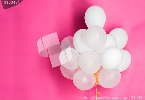 Image of close up of white helium balloons over pink