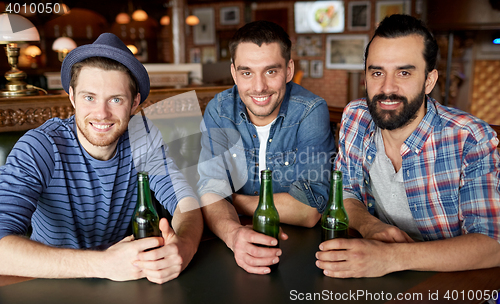 Image of happy male friends drinking beer at bar or pub