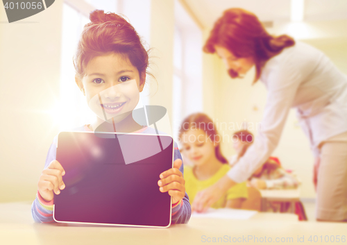 Image of little school girl with tablet pc over classroom