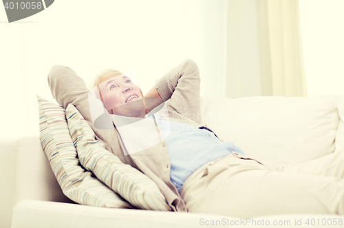 Image of happy senior woman resting on sofa at home