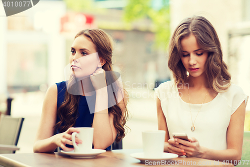 Image of women with smartphones and coffee at outdoor cafe
