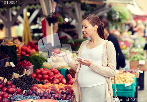 Image of pregnant woman with smartphone at street market