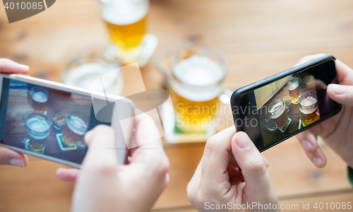 Image of close up of hands with smartphone picturing beer