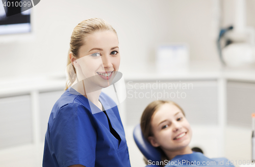 Image of happy female dentist with patient girl at clinic