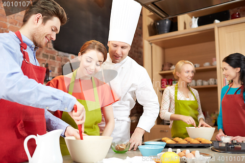 Image of happy friends and chef cook baking in kitchen