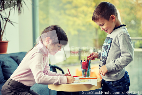 Image of happy little girl and boy drawing at home