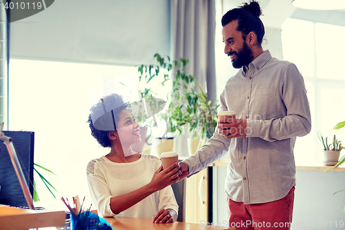 Image of happy man bringing coffee to woman in office