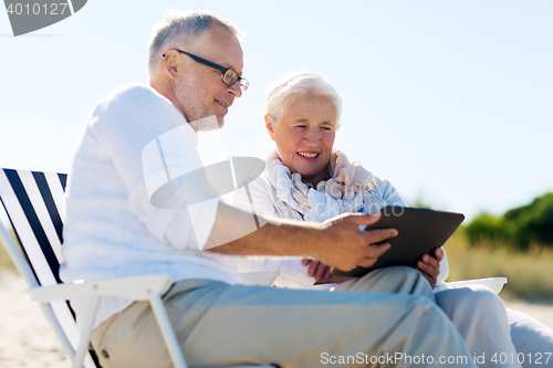 Image of happy senior couple with tablet pc on summer beach