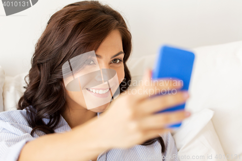 Image of happy woman taking selfie with smartphone at home