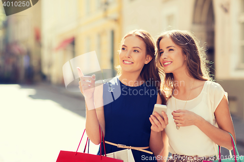 Image of happy women with shopping bags in city