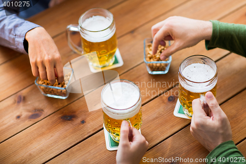 Image of close up of hands with beer mugs at bar or pub